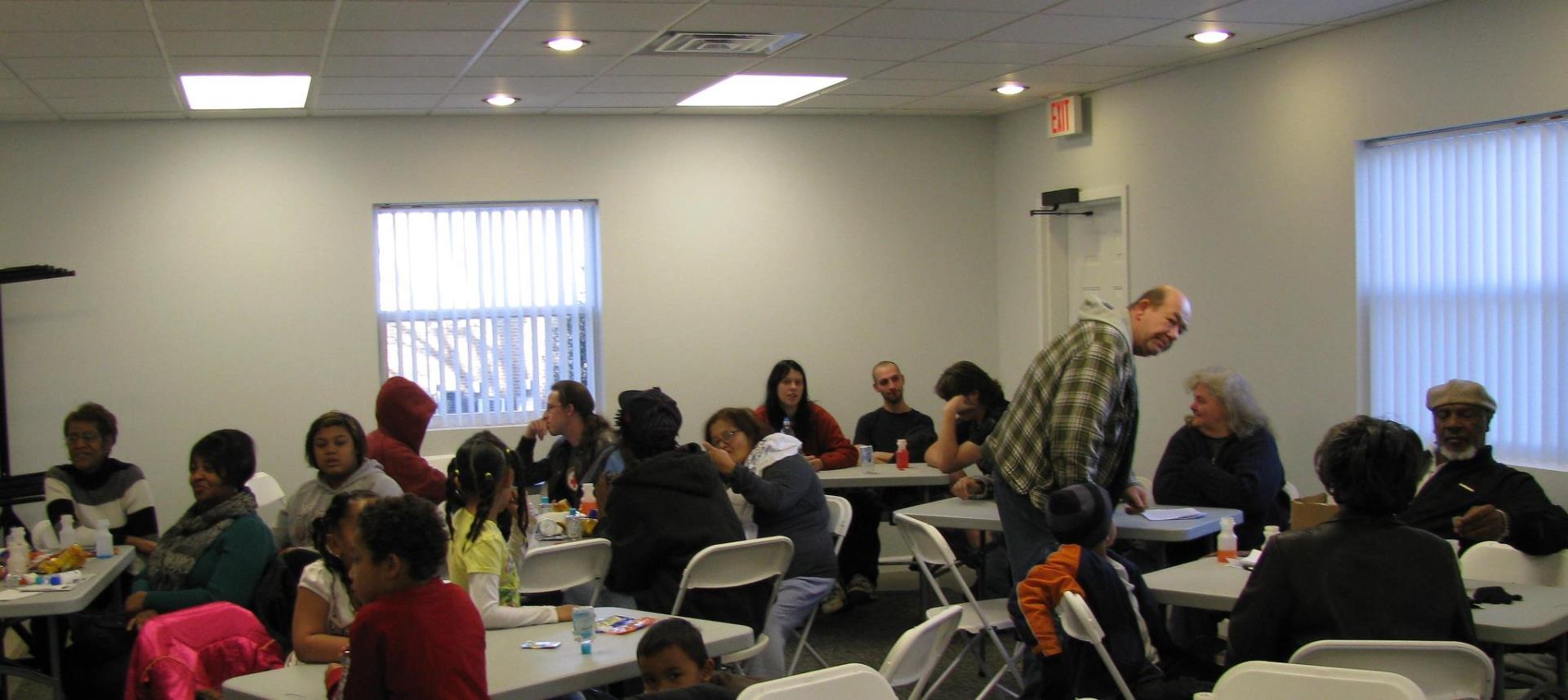 Neighbors of all ages gathered around tables for a community event inside the Bartley-Decatur Neighborhood Center
